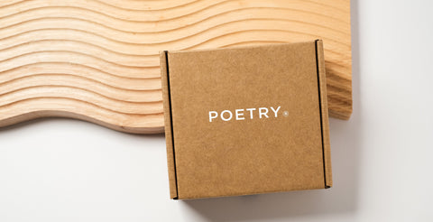 POETRY Skincare. Kraft cardboard FSC Certified packaging box with POETRY Skincare written on it.  sustainability foccussed with no plastic materials. Cardboard box is resting on a wooden board indented with a wavy design.